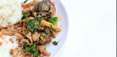 Tavada kızartılmış fesleğen bırak kıyılmış domuz eti, tavuk, kızarmış korunmuş yumurta ve havuç, sarı Mısır, pirinç ve beyaz arka plan üzerinde beyaz tabak kızarmış yumurta ile brokoli. Tay tarzında gıda.