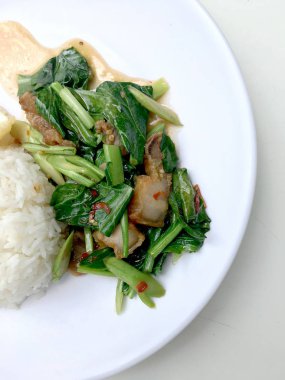 Fry stir Kai arazi ve gevrek domuz eti, beyaz arka plan üzerinde beyaz tabak kızarmış pilav pilav ile karıştırın. Tay tarzında gıda.