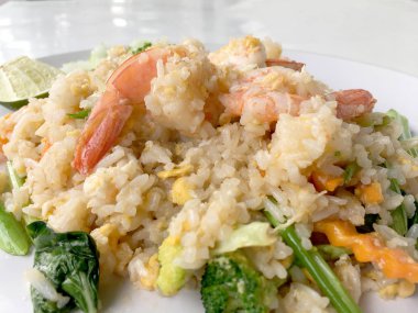 Limon ve beyaz arka plan üzerinde beyaz tabak içinde salatalık Fried rice karides otlar ve sebze ile servis. Dokuz Asya gıda yemekler bir dizi parçası. Tayland gıda.