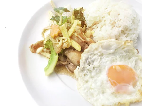 Tercampur sayuran digoreng dengan daging dan telur goreng dengan nasi di piring putih dengan latar belakang kayu. Makanan Thailand untuk kesehatan . — Stok Foto