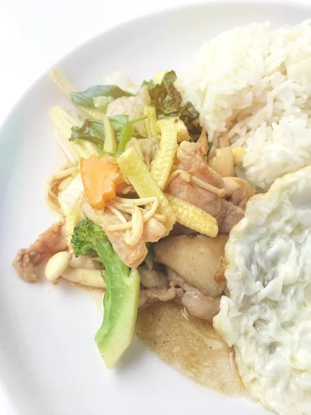 ผักรวมทอดกับเนื้อและไข่ทอดกับข้าวในจานสีขาวบนพื้นหลังไม้ อาหารไทยเพื่อสุขภาพ . — ภาพถ่ายสต็อก