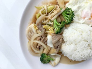 Tayland mutfağı. Tavada kızartılmış renkli sebze, soğan, brokoli, mantar etli pilav ve kızarmış yumurta beyaz arka plan üzerinde beyaz tabak içinde. Hızlı sokak restoran Tay tarzında gıda.