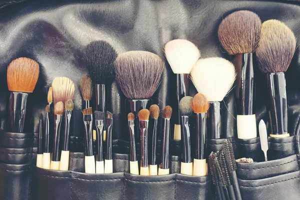 Professional makeup brushes cosmetic in tube, leather bag. close-up brush, makeup tools of , powder, set of different objects for makeup artist in their holder. Set of make up products arranged