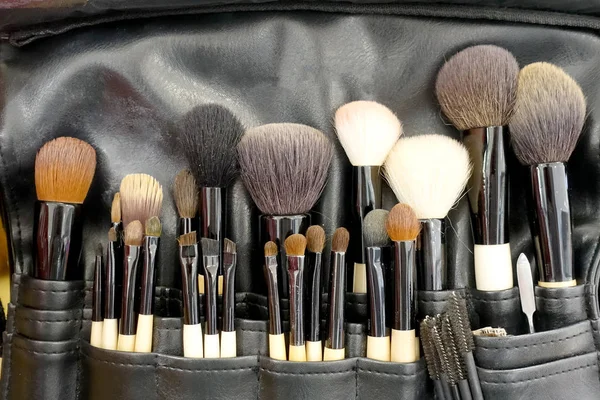 Professional makeup brushes cosmetic in tube, leather bag. close-up brush, makeup tools of , powder, set of different objects for makeup artist in their holder. Set of make up products arranged