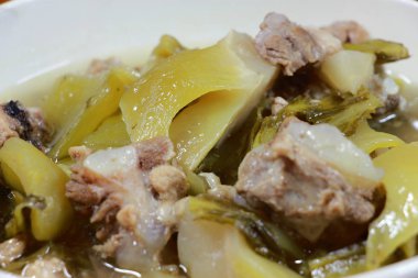 Yedek ripleri ve içinde ahşap masa üzerinde beyaz darbe çizgili domuz eti ile turşu marul çorbası. Tay geleneksel yerel Kuzey gıda.