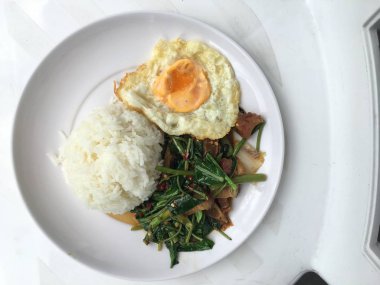 Fry stir Kai arazi ve gevrek domuz eti, beyaz arka plan üzerinde beyaz tabak kızarmış pilav pilav ile karıştırın. Tay tarzında gıda.