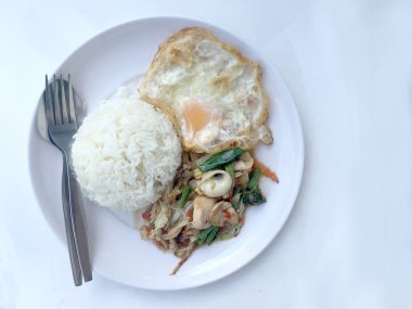 Kızarmış baharatlı deniz ürünleri fesleğen yaprakları ve karışık sebze ve pirinç yasemin beyaz tabak kızarmış yumurta ile kızarmış. Tay tarzında gıda.