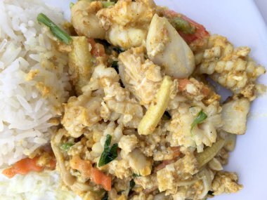 Deniz ürünleri, karides ve sarı toz köri pirinç ve kızarmış yumurta beyaz arka plan üzerinde beyaz tabakta kalamar tavada kızartılmış. Tay tarzında gıda.