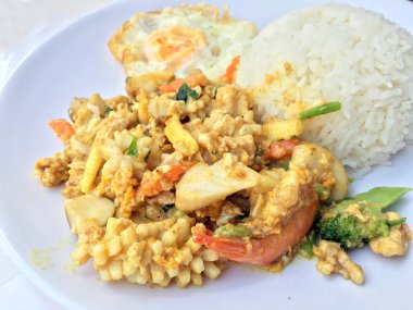 Deniz ürünleri, karides ve sarı toz köri pirinç ve kızarmış yumurta beyaz arka plan üzerinde beyaz tabakta kalamar tavada kızartılmış. Tay tarzında gıda.