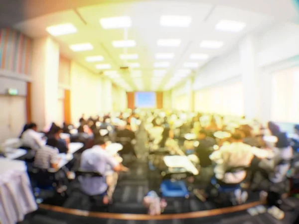 Education concept, Abstract blurred background image of students and business people  studying and discuss in large hall profession seminar with screen and projector for showing information.