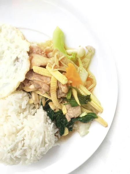 Tercampur sayuran digoreng dengan daging dan telur goreng dengan nasi di piring putih dengan latar belakang kayu. Makanan Thailand untuk kesehatan . — Stok Foto