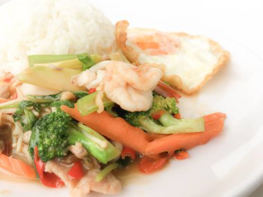 Kızarmış lezzetli shimp ve kızarmış yumurta beyaz arka plan üzerinde beyaz tabak pirinç Tay ev yapımı yemek ya da restoranda yemek tarifi olarak hizmet ile karışık sebze sote. Tay tarzında gıda.