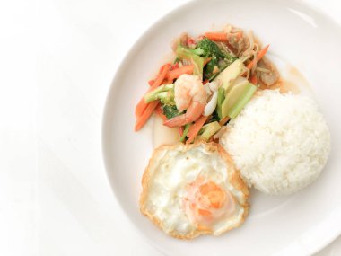 Kızarmış lezzetli shimp ve kızarmış yumurta beyaz arka plan üzerinde beyaz tabak pirinç Tay ev yapımı yemek ya da restoranda yemek tarifi olarak hizmet ile karışık sebze sote. Tay tarzında gıda.