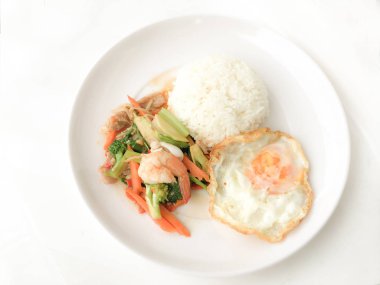 Kızarmış lezzetli shimp ve kızarmış yumurta beyaz arka plan üzerinde beyaz tabak pirinç Tay ev yapımı yemek ya da restoranda yemek tarifi olarak hizmet ile karışık sebze sote. Tay tarzında gıda.