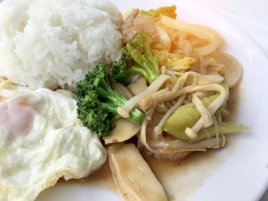 Tayland mutfağı. Tavada kızartılmış renkli sebze, soğan, brokoli, mantar etli pilav ve kızarmış yumurta beyaz arka plan üzerinde beyaz tabak içinde. Hızlı sokak restoran Tay tarzında gıda.