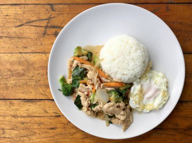 karışık sebze ve pirinç eski ahşap masa üzerinde beyaz tabak içinde Tay tarzında kızarmış yumurta ile tavada kızartılmış tavuk. Asya Tayland gıda.