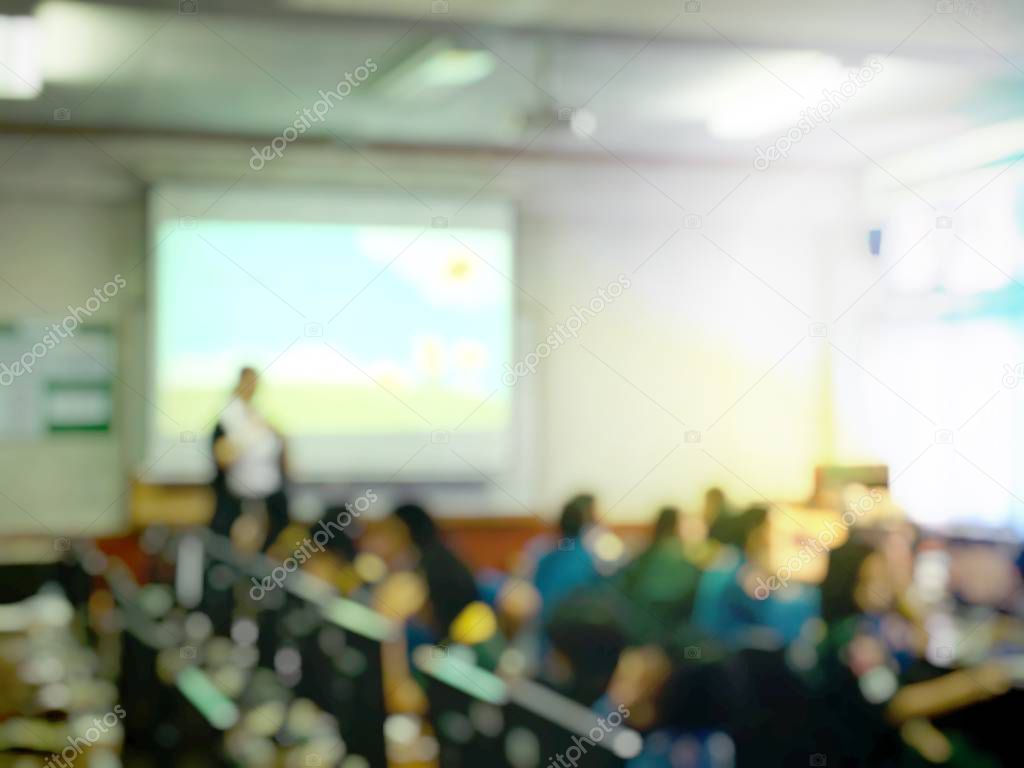 blurred image of education people and business people sitting in conference room for profession seminar and the speaker is presenting with screen projector and idea sharing with the content activity.