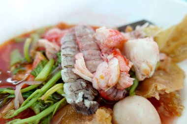 Yentafo baharatlı erişte çorbası, sıcak ve baharatlı karışık deniz ürünleri, kerevit, karides. Tablo arka plan üzerinde beyaz kase Asya baharatlı deniz ürünleri şehriye çorbası. Tay tarzında şehriye ve sokak gıda Tayland.