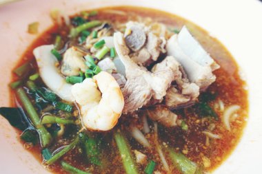 Domuz kemik kerevit, karides ile baharatlı deniz ürünleri erişte çorbası. Ahşap masa arka plan üzerinde pembe kase Asya gıda. Tay tarzı erişte ve Tayland sokak gıda. üst görünüm