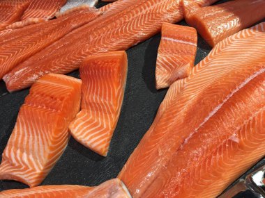 Çiğ somon dilimlenmiş veya taze somon. Somon fileto bir patchwork etkisi ile görüntülenen pazarında Satılık. Satılık süpermarket olan et dilimleri içinde siyah bir tepsi birçok taze somon balık.