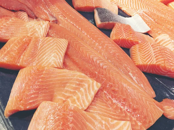 Çiğ somon dilimlenmiş veya taze somon. Somon fileto bir patchwork etkisi ile görüntülenen pazarında Satılık. Satılık süpermarket olan et dilimleri içinde siyah bir tepsi birçok taze somon balık.