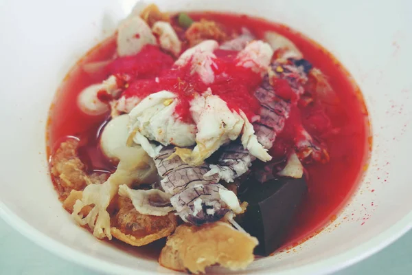 Yentafo Spicy noodle soup,hot and spicy ,with mix seafood, crayfish, shrimp. Asian spicy seafood noodle soup in white bowl on table background. Thai style noodle and street food of Thailand.