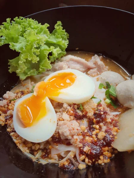 泰国辣猪肉面汤与椰奶 蔬菜香草和温泉塔玛戈鸡蛋在黑碗芝麻和花生在木桌上 从上面看 — 图库照片