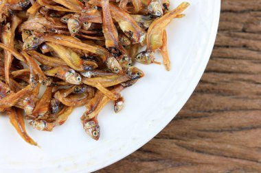 Kızarmış dev yayın balığı ve kızartılmış küçük balıklar (Minnow) geleneksel Tayland tarifleri kırsal ahşap arka planda beyaz tabakta. Tayland 'da popüler, Tayland' ın önemli ihracat ürünü.