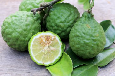 Tahta masa arkasında taze Bergamot meyvesi ve bergamot yaprakları grubu