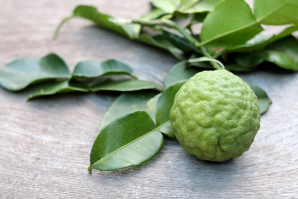 Tahta masa arkasında taze Bergamot meyvesi ve bergamot yaprakları grubu