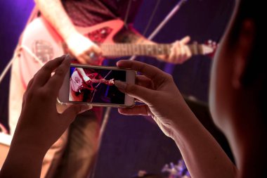kadının el elektro gitar ile müzikal bir sunum kayıt seyirciler bir akıllı telefon tutarak yakın çekim ekranda