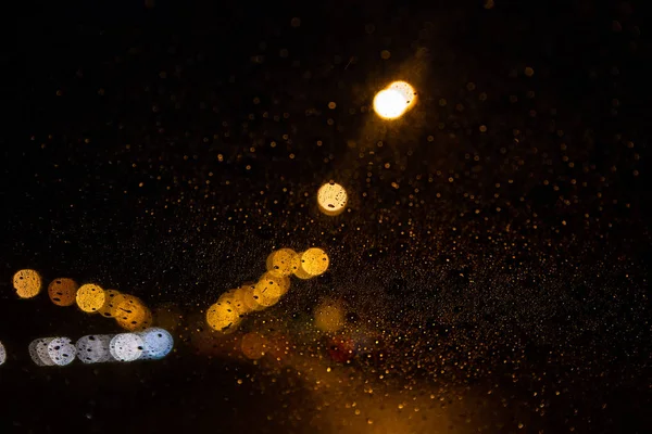 Luci di via attraverso il parabrezza con gocce di pioggia — Foto Stock