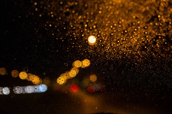Luzes de rua através do pára-brisas com gotas de chuva — Fotografia de Stock