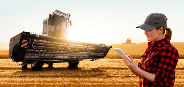 Mujer agricultora con tableta digital en un fondo de cosechadora —  Fotos de Stock