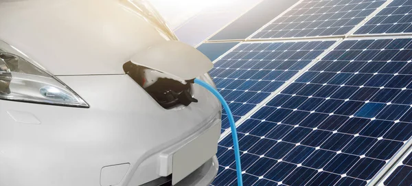 太陽光パネルと風力タービンの背景に接続された充電ケーブルを備えた電気自動車の閉鎖 クリーン再生可能エネルギーの源 — ストック写真