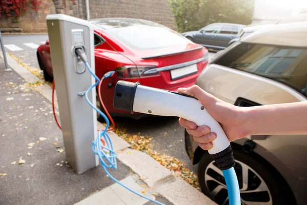 電気自動車を背景に充電器で手 — ストック写真