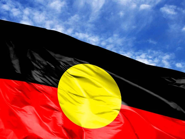 waving flag of Australian Aboriginal close up against blue sky