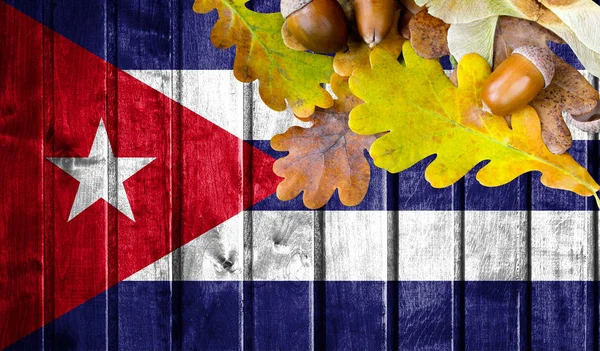 Cuba flag on autumn wooden background with leaves and good place for your text.