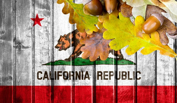 State of California flag on autumn wooden background with leaves and good place for your text.