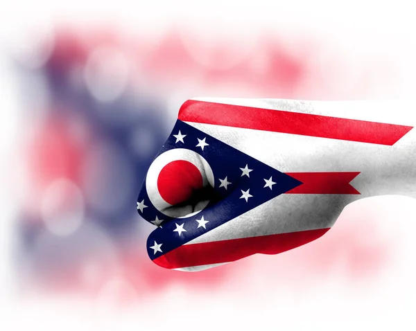 Flag of State of Ohio painted on male fist, strength,power,concept of conflict. On a blurred background.