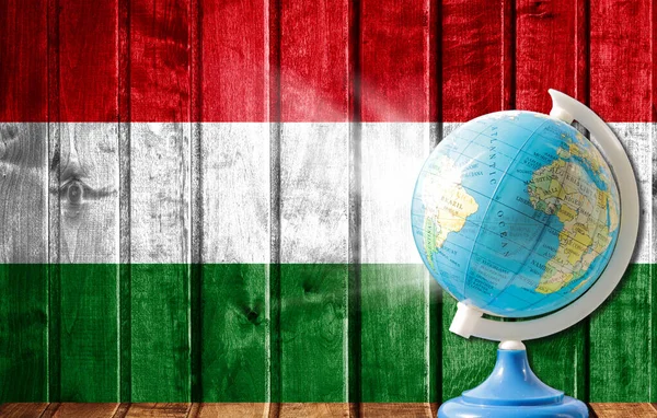 Globe with a world map on a wooden background with the image of the flag of Hungary. The concept of travel and leisure abroad.