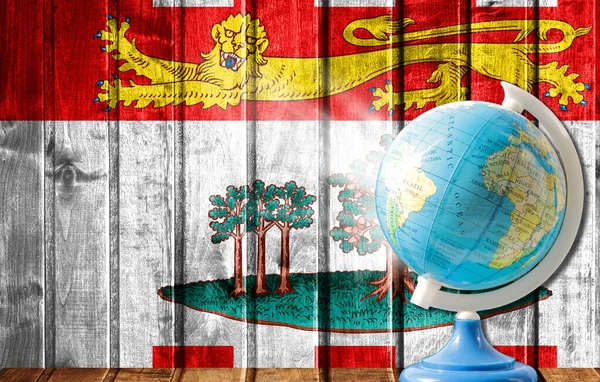 Globe with a world map on a wooden background with the image of the flag of Prince Edward Island. The concept of travel and leisure abroad.