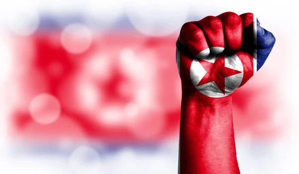 Flag of North Korea painted on male fist, strength,power,concept of conflict. On a blurred background with a good place for your text.