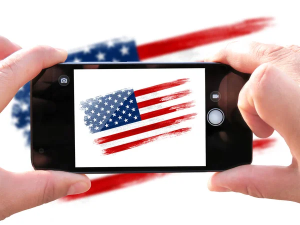 brush painted flag of USA. The hands of men make a photo from the phone. Shooting from the smartphone.