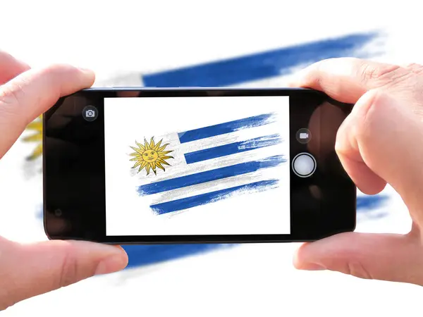 brush painted flag of Uruguay. The hands of men make a photo from the phone. Shooting from the smartphone.