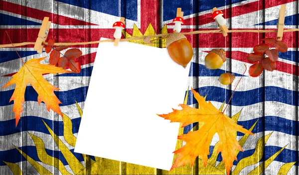 British Columbia flag on autumn wooden background with leaves and good place for your text.