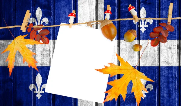 Quebec flag on autumn wooden background with leaves and good place for your text.