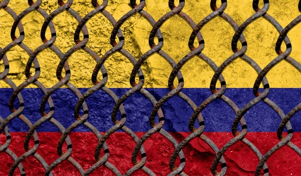 Immigration policy regarding migrants, illegal immigrants and refugees. Steel grid on the background of the flag of Colombia