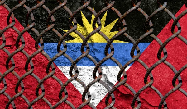 Immigration policy regarding migrants, illegal immigrants and refugees. Steel grid on the background of the flag of Antigua and Barbuda