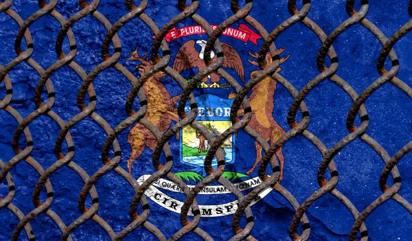 Immigration policy regarding migrants, illegal immigrants and refugees. Steel grid on the background of the flag State of Massachusetts